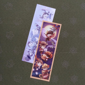 Photo of a double-sided bookmark design by TB (tangentburd) for the TF2021 calendar zine. One side features RED team with an autumn theme; the other features BLU team and Miss Pauling with a winter theme.